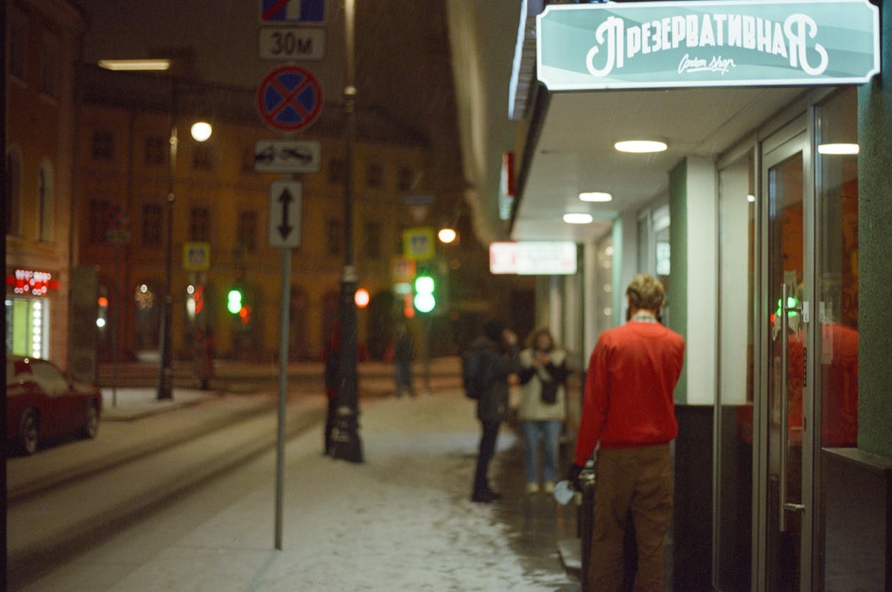 Capturing a snowy winter evening on a Moscow street with people and shop signs illuminated.