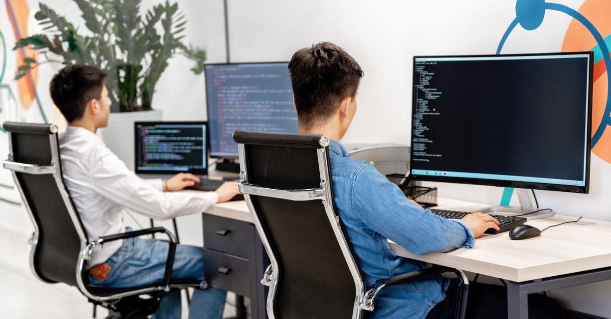 Custom Software & Mobile App Development Services in Kuala Lumpur, Malaysia Two male developers at desks programming in a modern office workspace with large monitors.