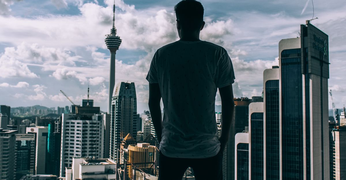 A silhouette of a man overlooking the Kuala Lumpur skyline, featuring the iconic KL Tower.