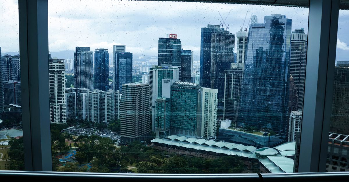 Overcast view of Kuala Lumpur's modern skyline through a rain-speckled window.