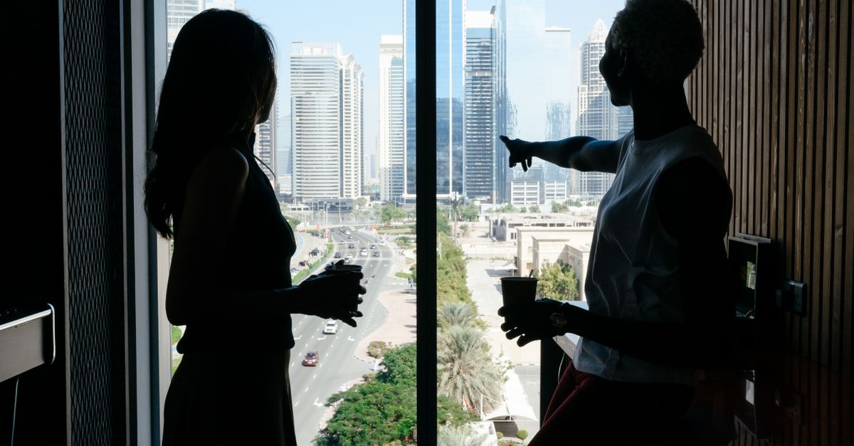 Finding Expert iOS Android App Developers in Kuala Lumpur: Guide 2026 Side view of anonymous diverse business partners with coffee talking about job while admiring tall contemporary buildings of large megapolis