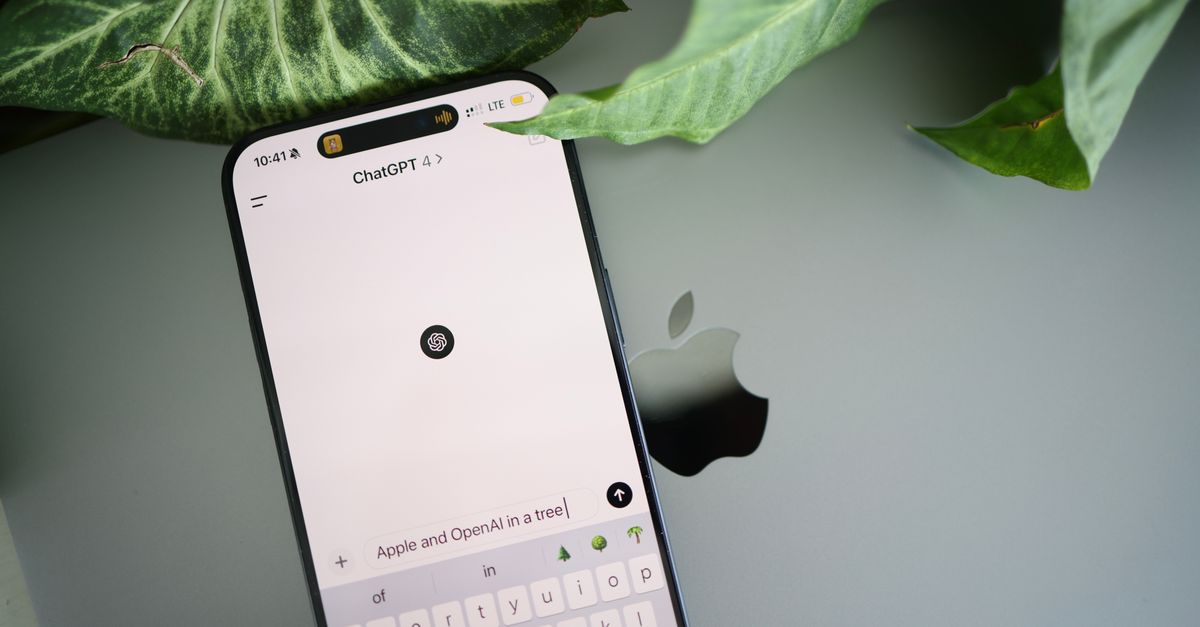A smartphone shows a ChatGPT interface placed on an Apple laptop in a leafy environment.