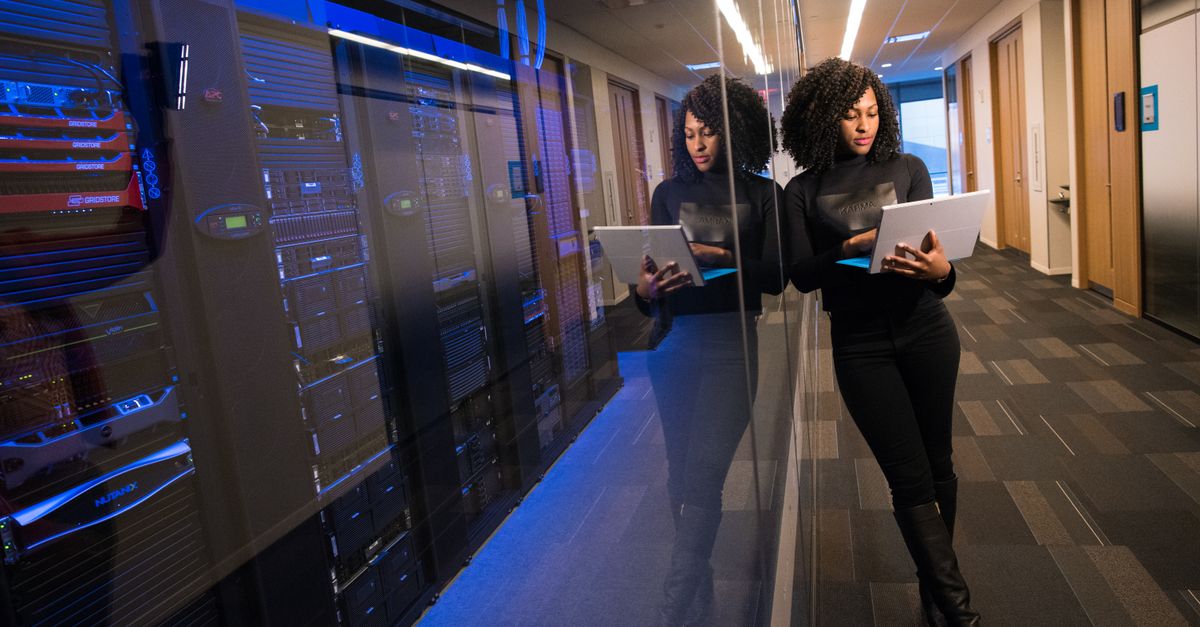 Managed IT Infrastructure Services in Kuala Lumpur: Expert Guide for Malaysian Businesses A woman using a laptop navigating a contemporary data center with mirrored servers.