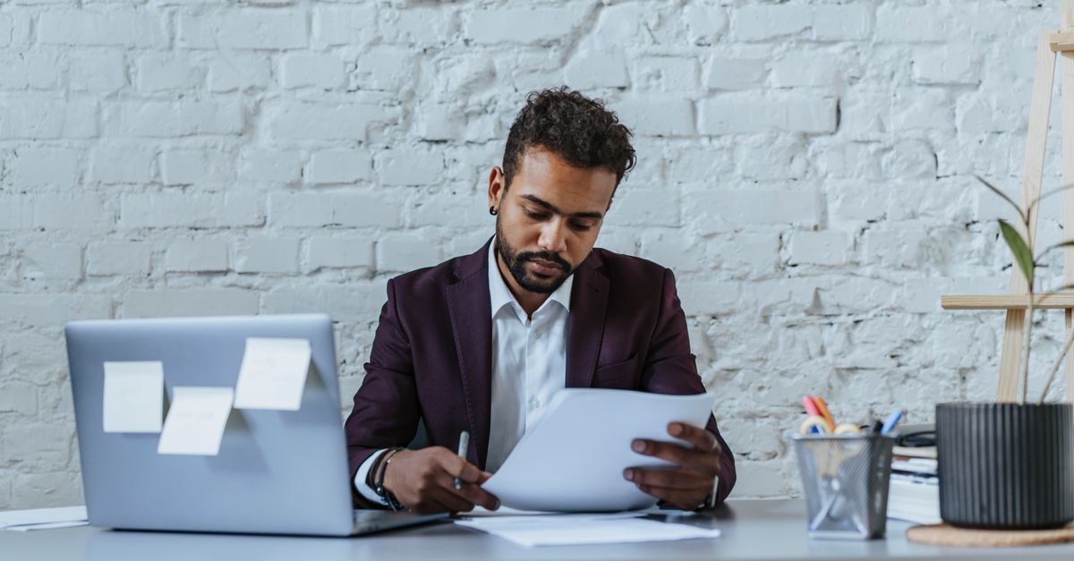 Stop Doing Repetitive Work: AI Workflow Automation Strategies for New York Businesses A professional man reviews documents in a modern office setting, focused on his work.